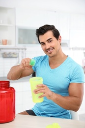 Photo of Young athletic man preparing protein shake in kitchen