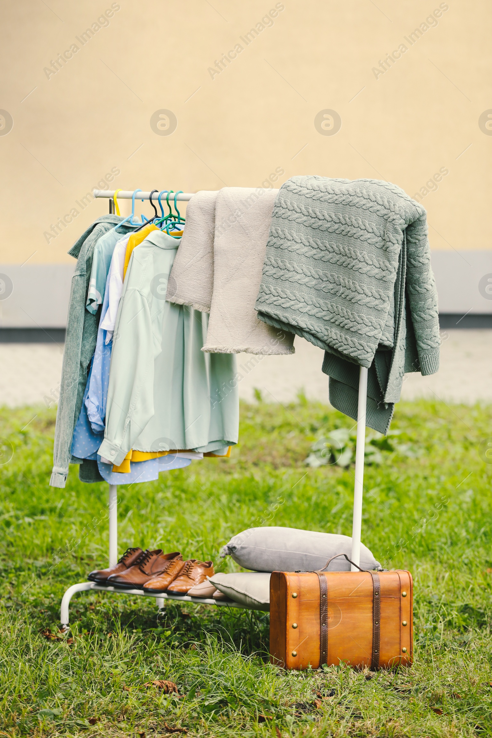 Photo of Clothing rack with different garments in yard. Garage sale