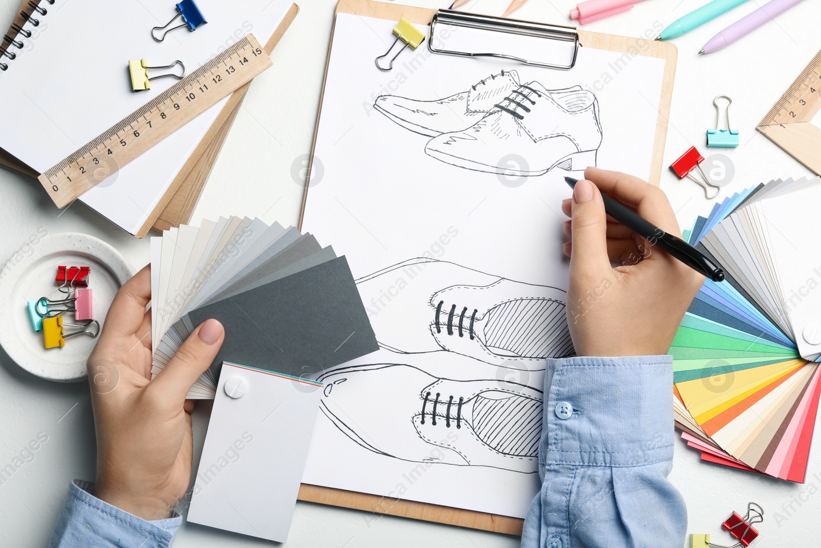 Photo of Fashion designer drawing shoes at table, top view