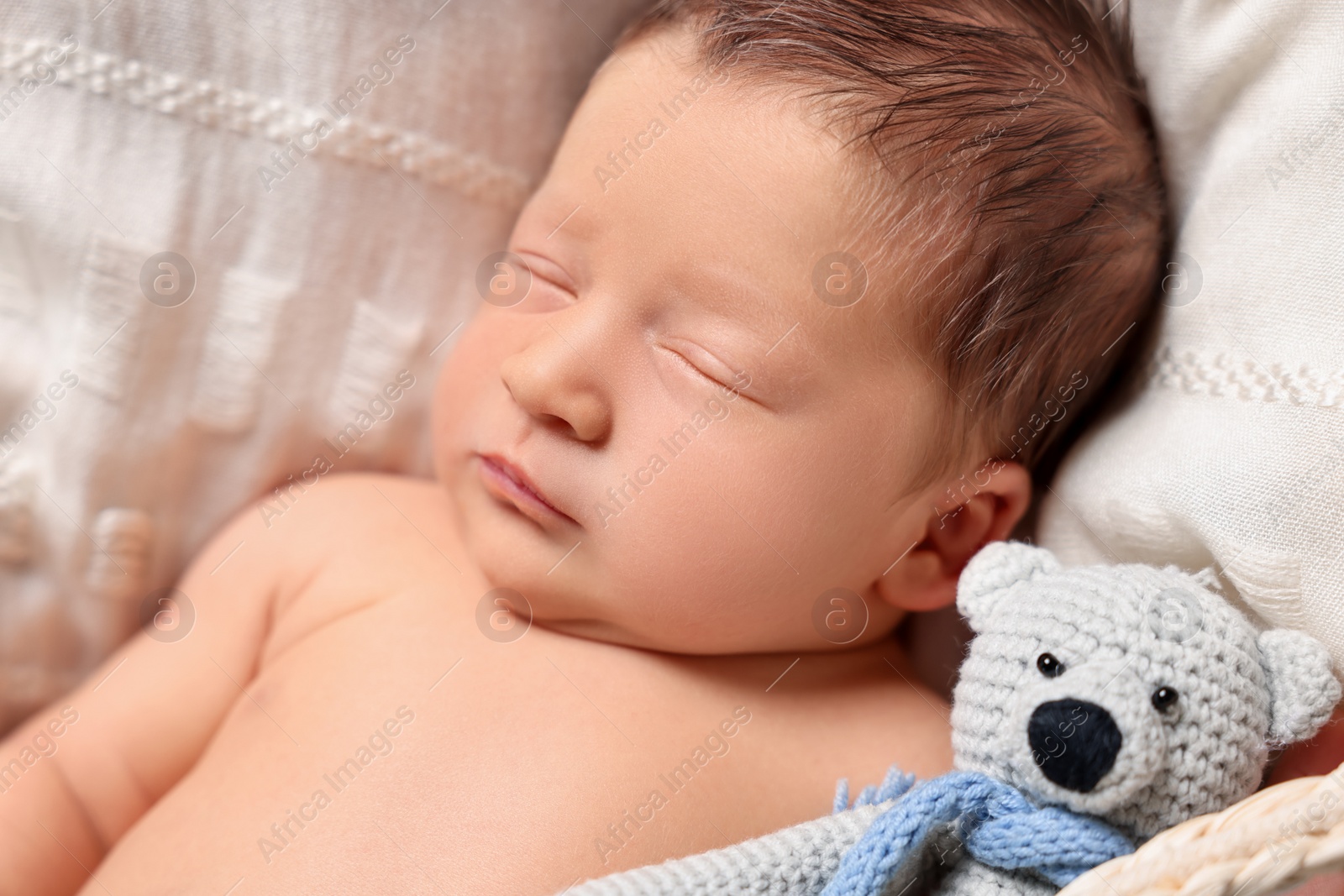 Photo of Cute newborn baby sleeping with toy bear on white blanket, closeup