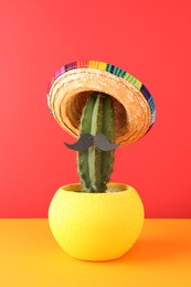 Cactus with Mexican sombrero hat and fake mustache on color background