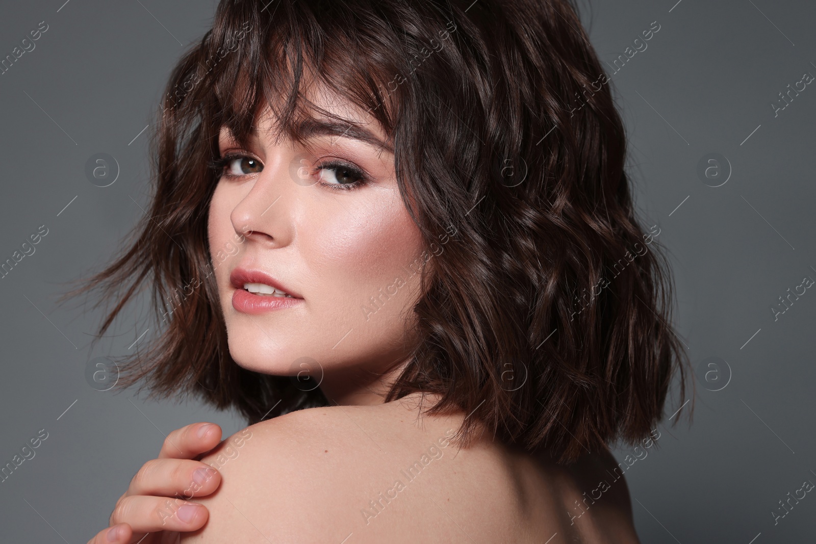 Photo of Portrait of beautiful young woman with wavy hairstyle on grey background