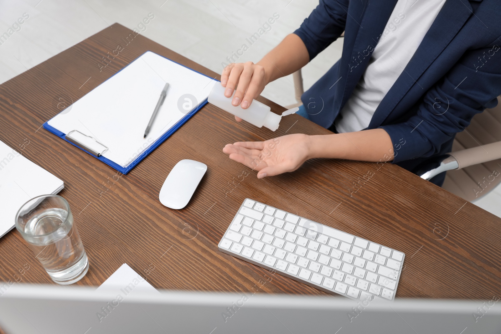 Photo of Office employee applying hand sanitizer at workplace, closeup