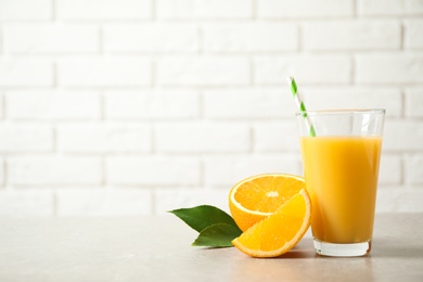 Photo of Glass of orange juice and fresh fruits on light table. Space for text