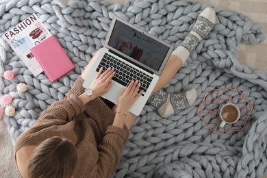 Photo of Woman holding laptop with open beauty blogger site on floor, top view