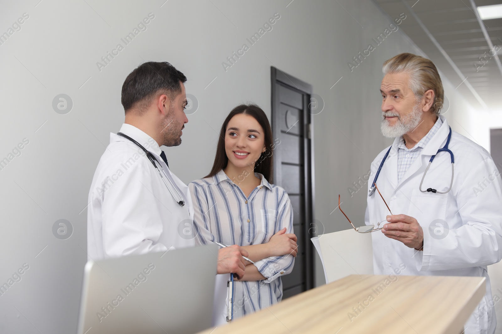 Photo of Doctors consulting patient near reception desk in clinic hall