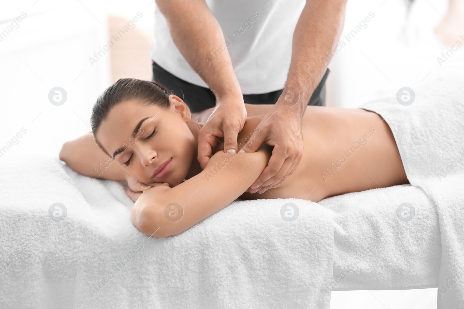 Photo of Relaxed woman receiving back massage in wellness center