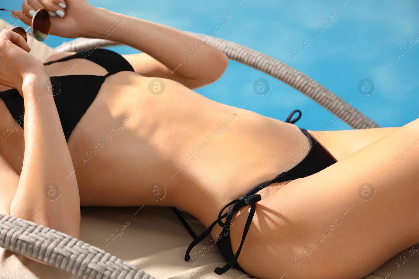 Photo of Young woman in stylish black bikini near swimming pool, closeup