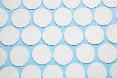 Many cotton pads on light blue background, flat lay