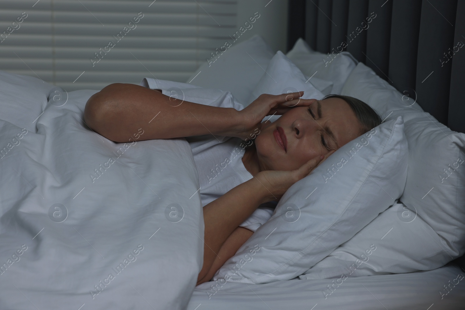 Photo of Woman suffering from headache in bed at night