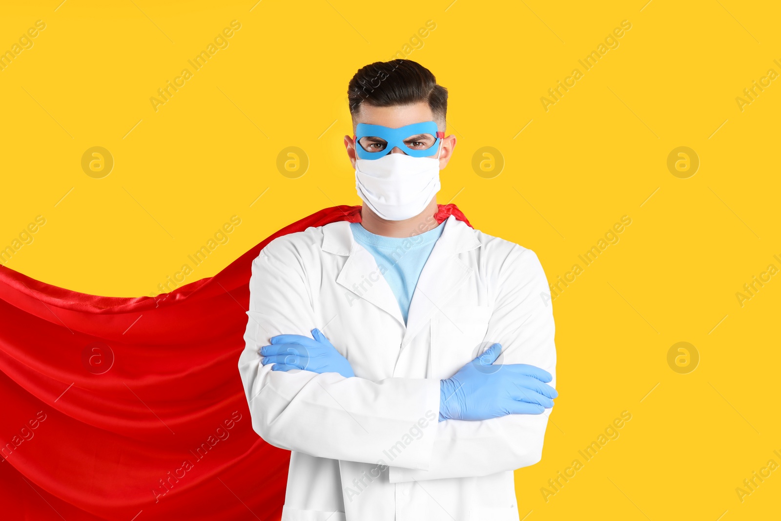 Photo of Doctor wearing face mask and cape on yellow background. Super hero power for medicine