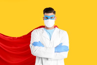 Doctor wearing face mask and cape on yellow background. Super hero power for medicine