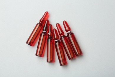 Photo of Glass ampoules with liquid on white background, top view