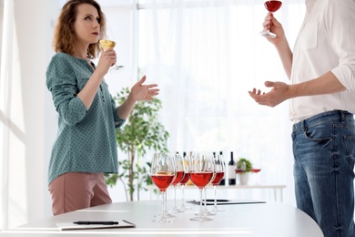 Photo of Young couple tasting wine at table indoors