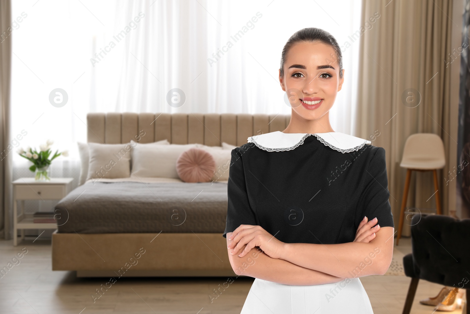 Image of Beautiful chambermaid near bed in hotel room