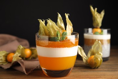 Photo of Delicious dessert decorated with physalis on wooden table