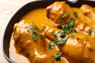 Photo of Tasty chicken curry with parsley on wooden table, closeup