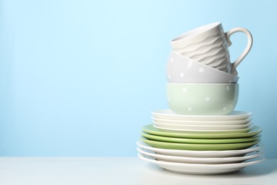 Photo of Beautiful ceramic dishware and cup on white table, space for text