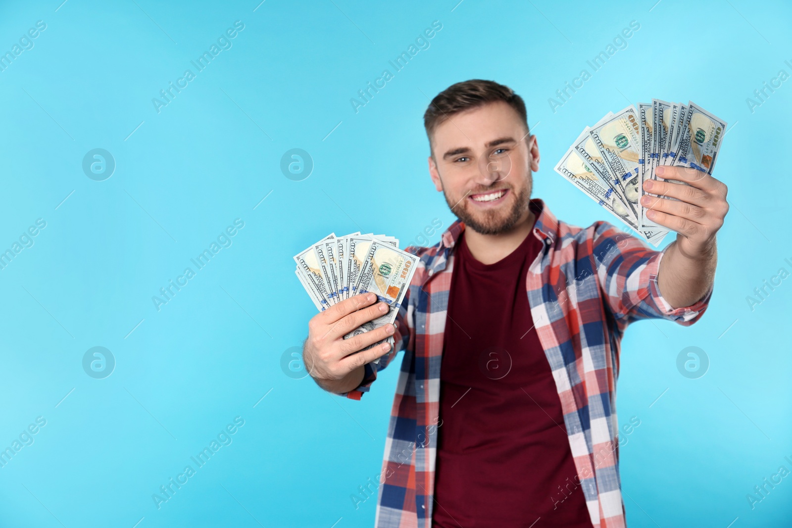 Photo of Portrait of happy young man with money on color background. Space for text