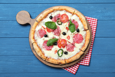 Photo of Delicious pizza Diablo and napkin on blue wooden background, top view