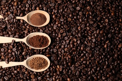 Photo of Spoons with different types of coffee on roasted beans, flat lay. Space for text