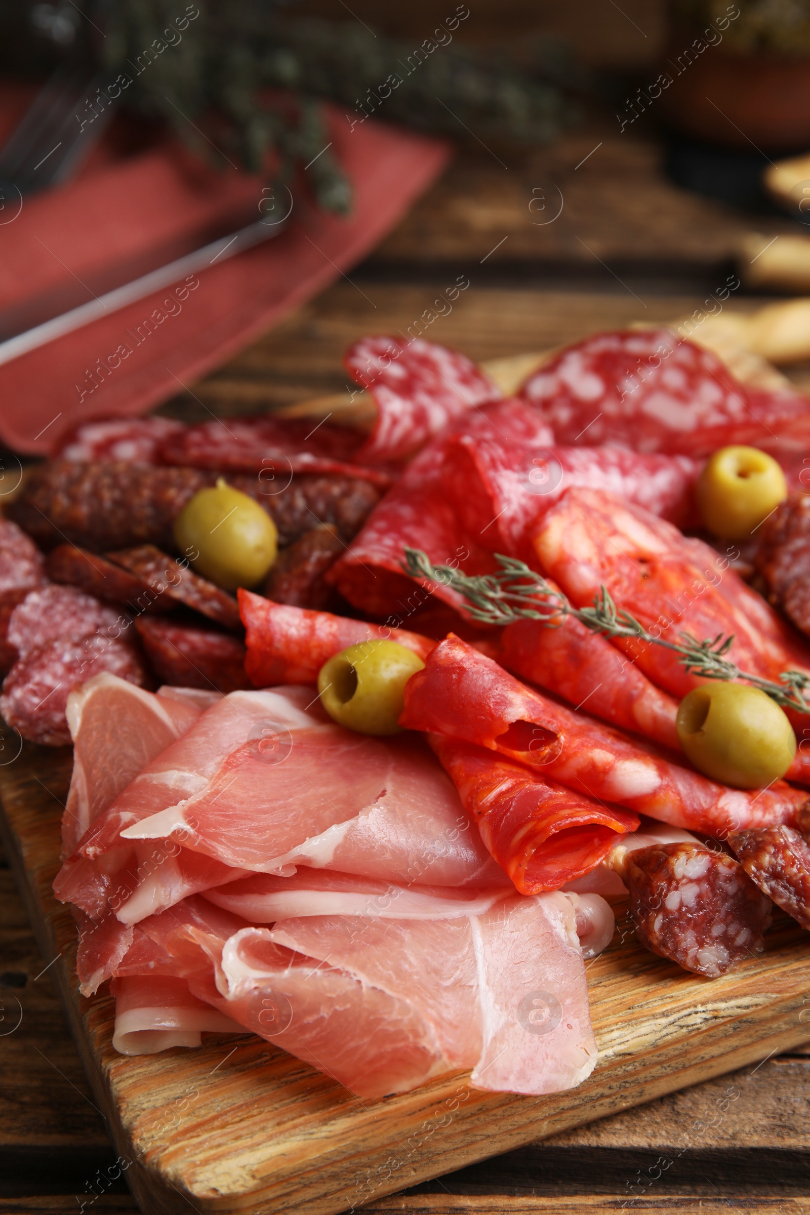 Photo of Tasty prosciutto with other delicacies served on wooden table