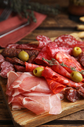 Photo of Tasty prosciutto with other delicacies served on wooden table
