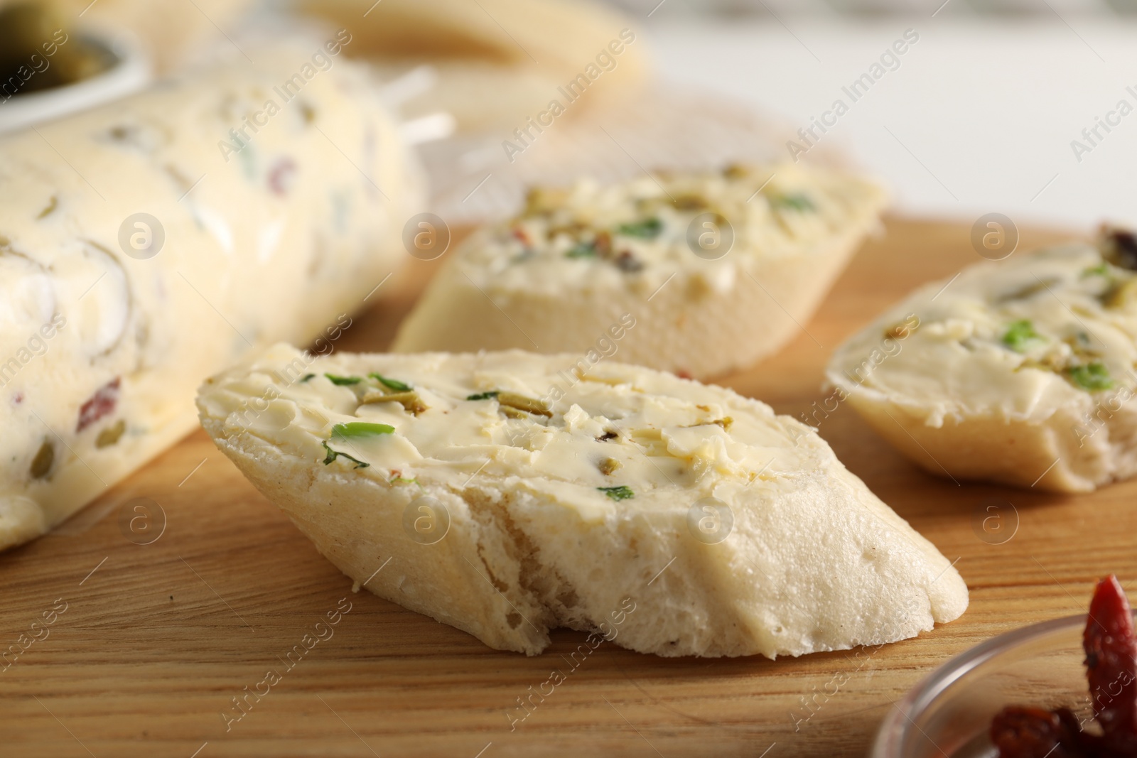 Photo of Tasty butter with olives, green onion and bread on wooden board, closeup