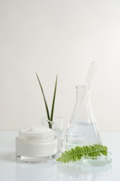 Photo of Organic cosmetic product, natural ingredients and laboratory glassware on white table