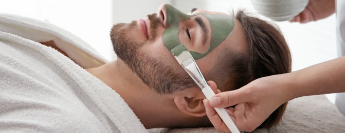 Image of Cosmetologist applying mask on client's face in spa salon. Banner design