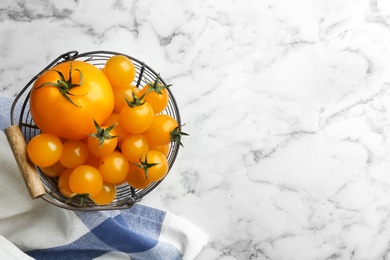 Photo of Ripe yellow tomatoes on white marble table, top view. Space for text