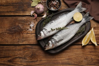 Sea bass fish and ingredients on wooden table, flat lay. Space for text