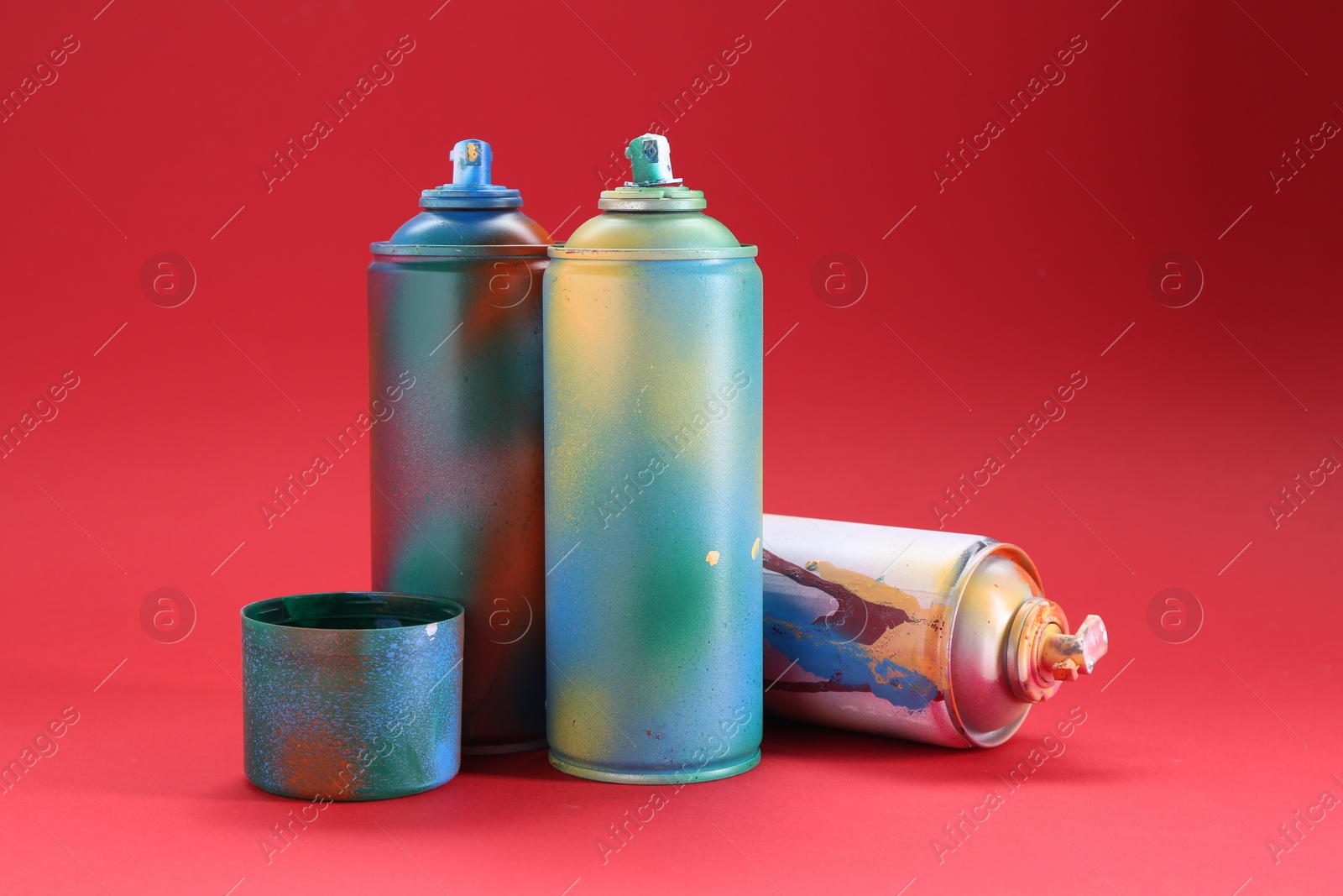 Photo of Bright spray paint cans with cap on red background