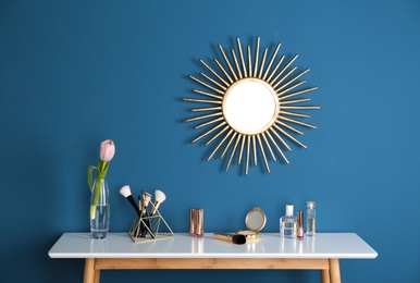 Dressing table with spring flower and makeup products at blue wall