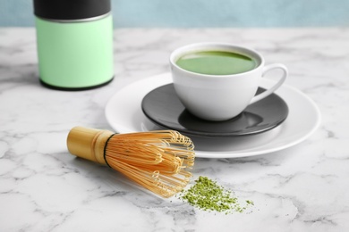 Cup of fresh matcha tea and chasen on table