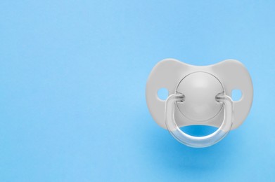 Photo of One new baby pacifier on light blue background, top view. Space for text