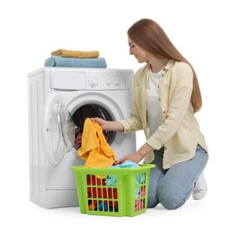 Beautiful young woman taking laundry out of washing machine on white background