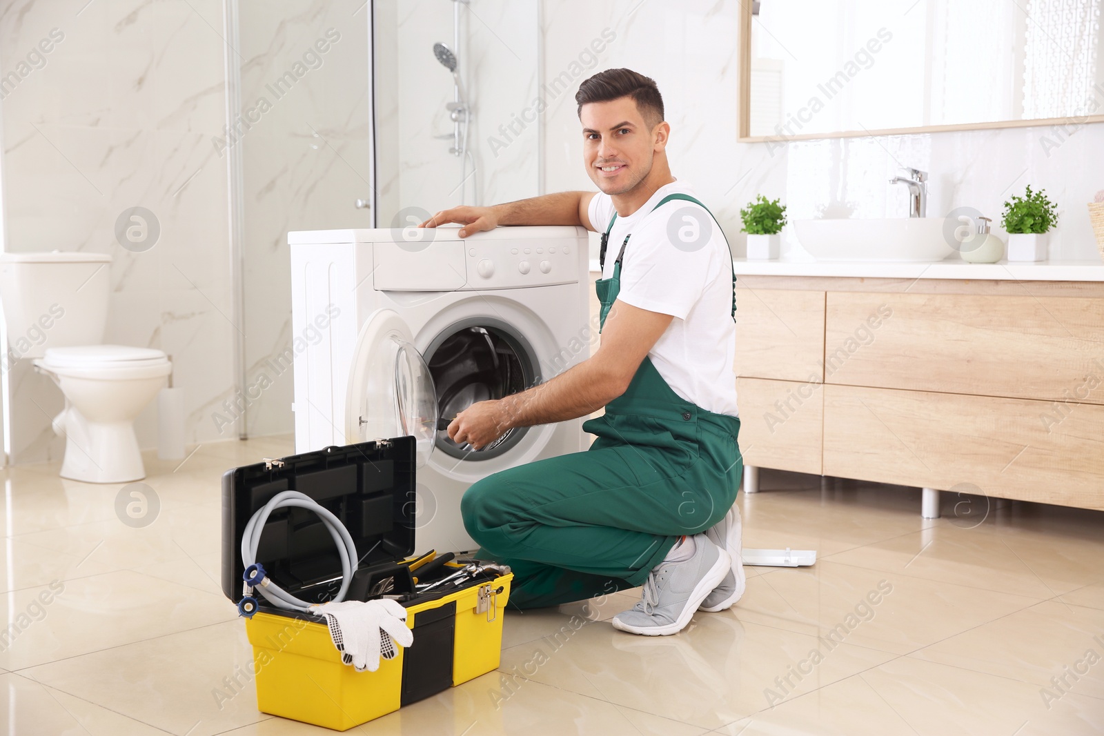 Photo of Professional plumber repairing washing machine in bathroom