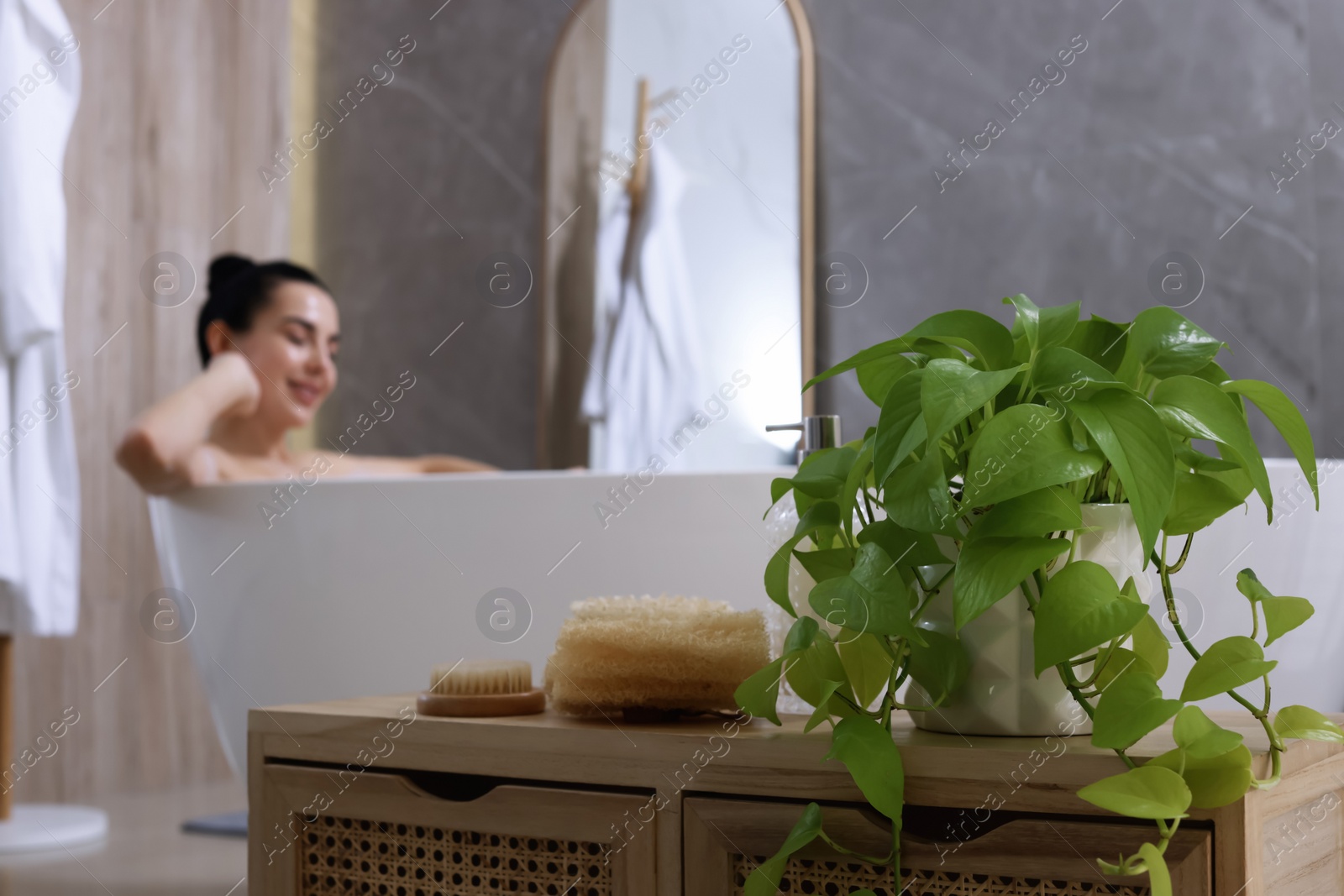 Photo of Woman taking bath indoors, focus on body care products