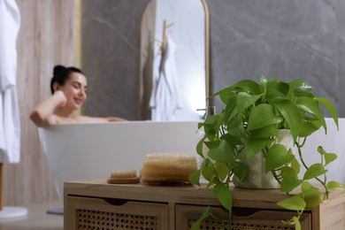 Photo of Woman taking bath indoors, focus on body care products