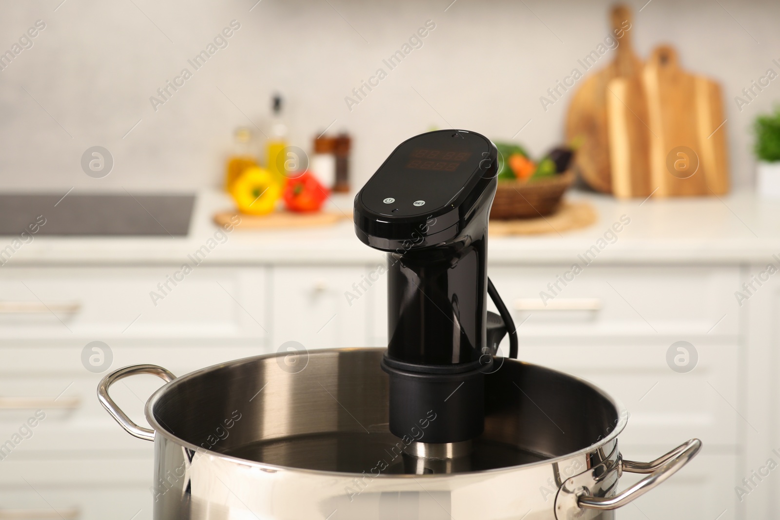 Photo of Pot with sous vide cooker in kitchen, closeup. Thermal immersion circulator