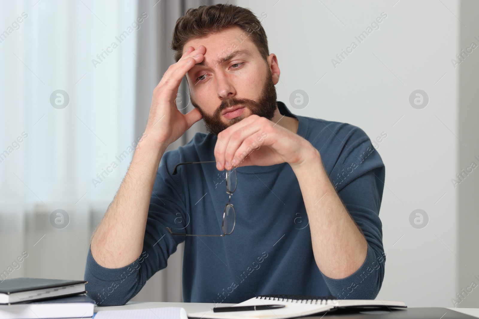 Photo of Overwhelmed man with glasses at table indoors