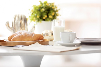 Tasty breakfast with fresh croissants and cup of coffee on table