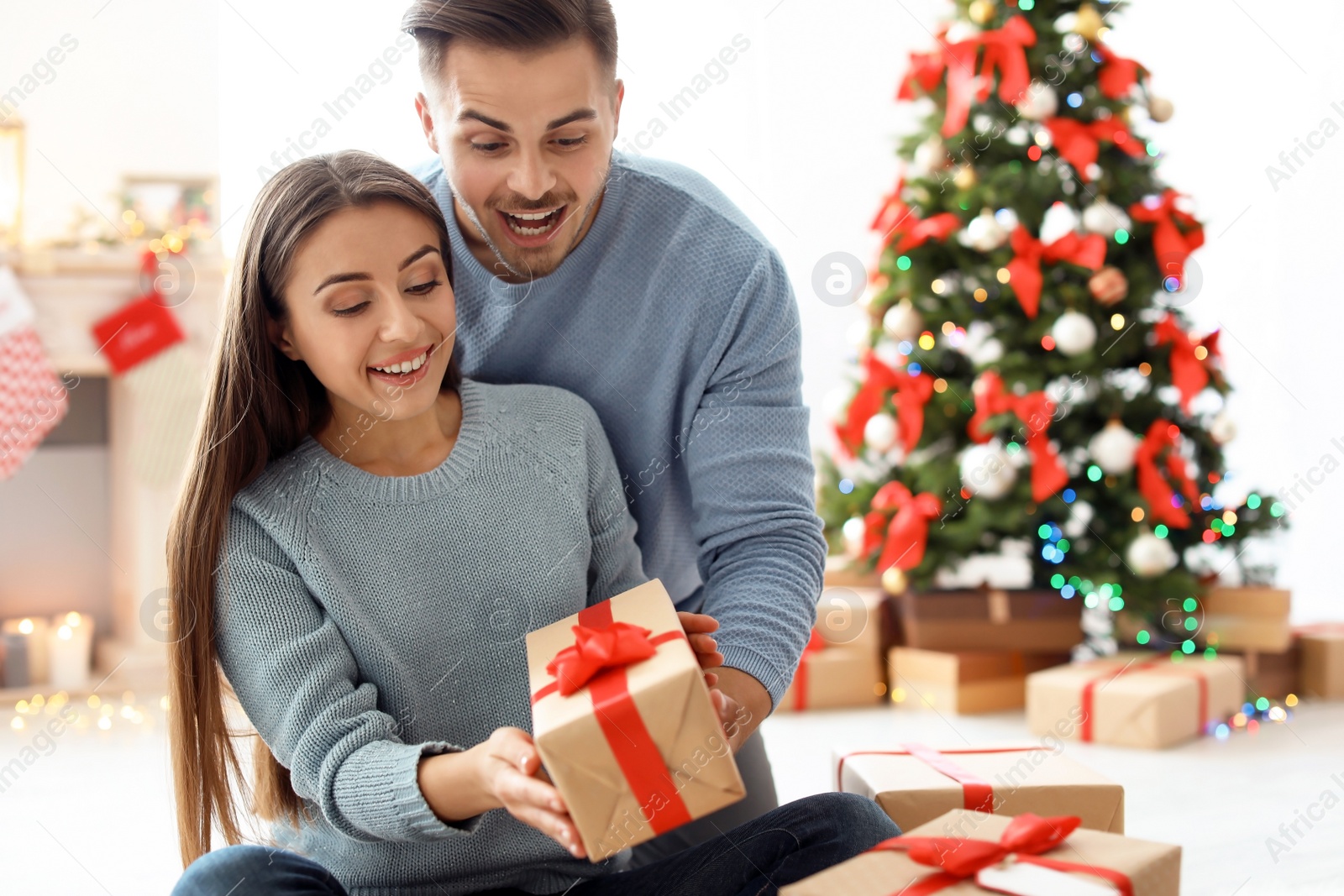 Photo of Young man giving Christmas gift to his girlfriend at home