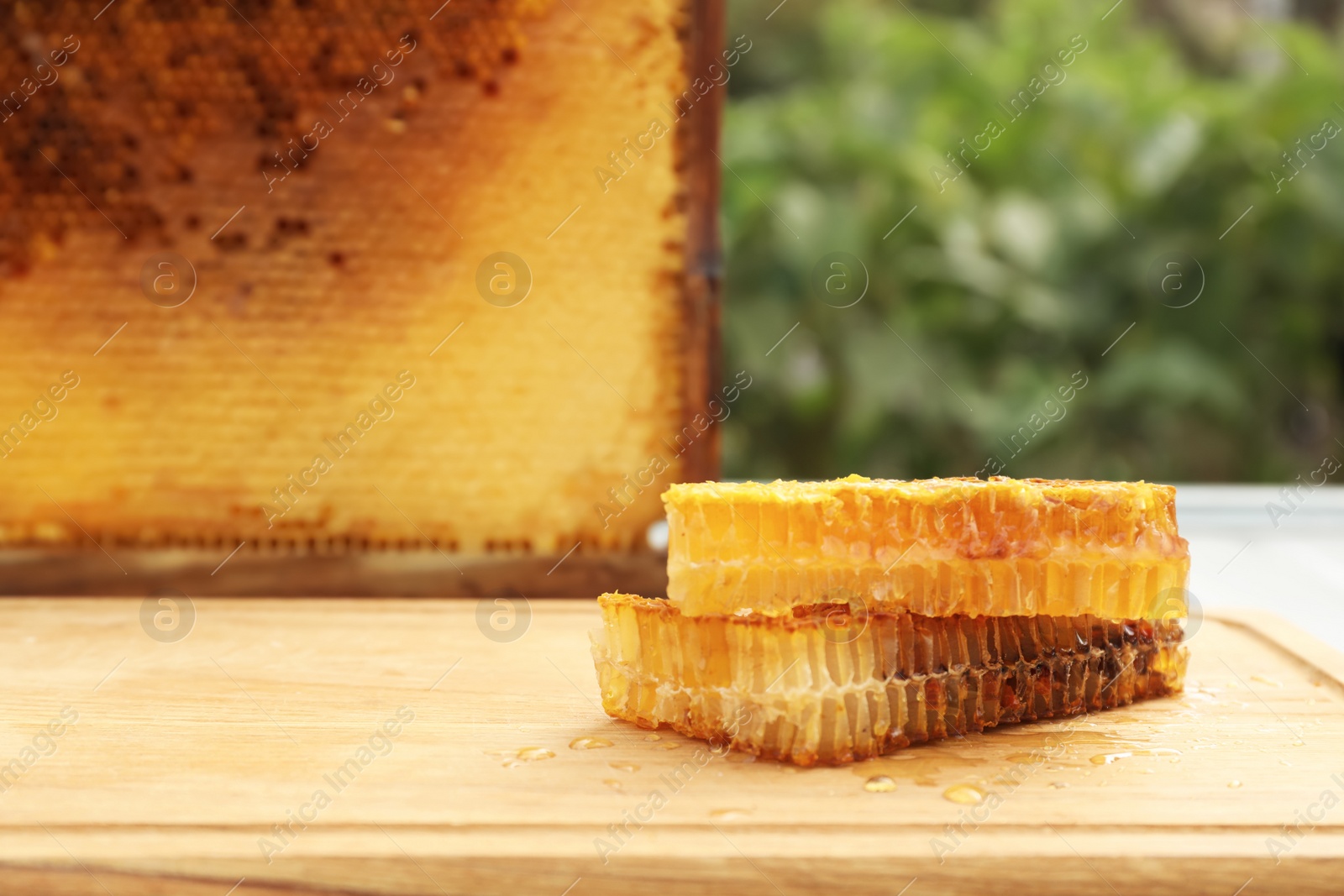 Photo of Fresh delicious honeycombs on wooden table outdoors. Space for text