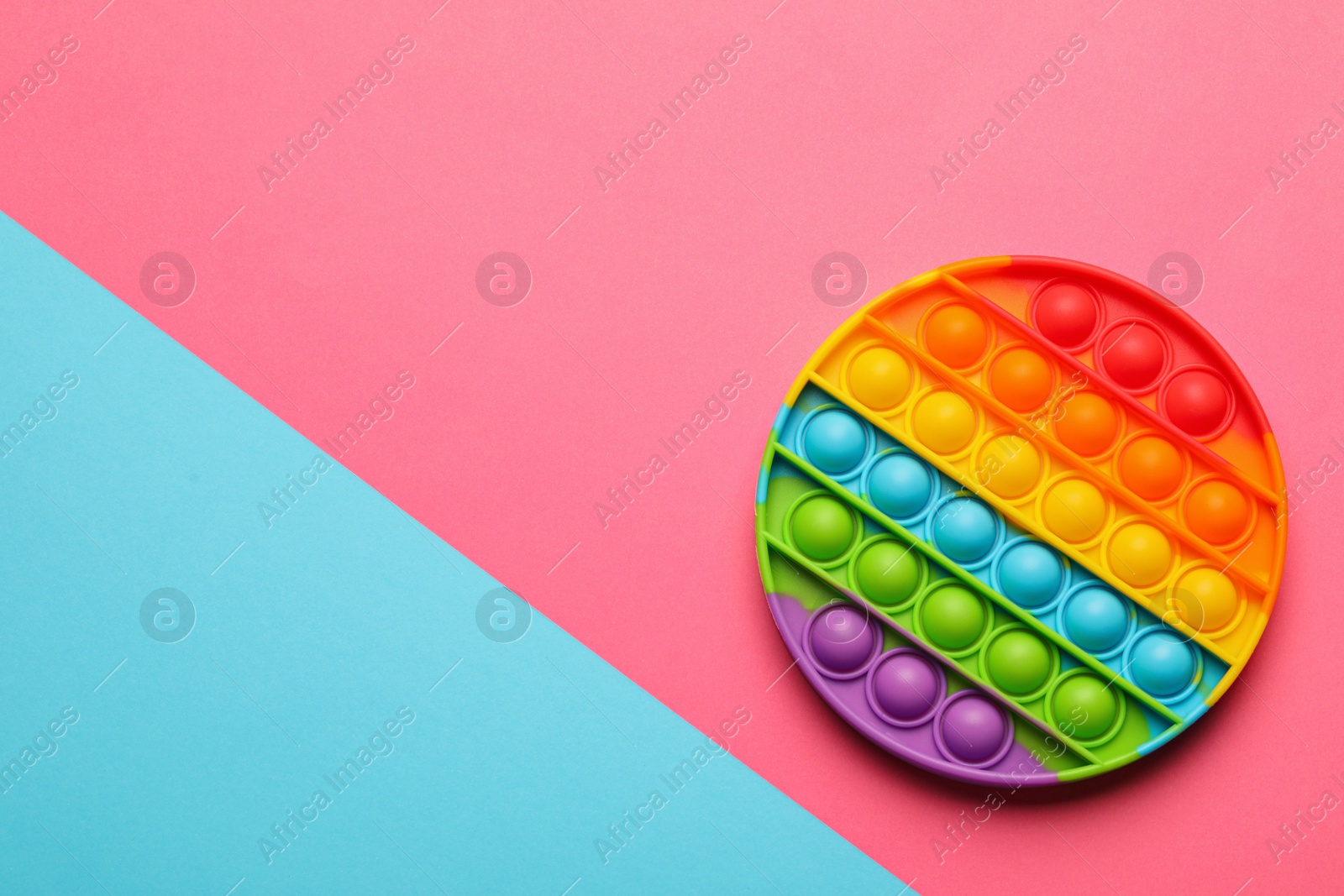 Photo of Rainbow pop it fidget toy on color background, top view. Space for text