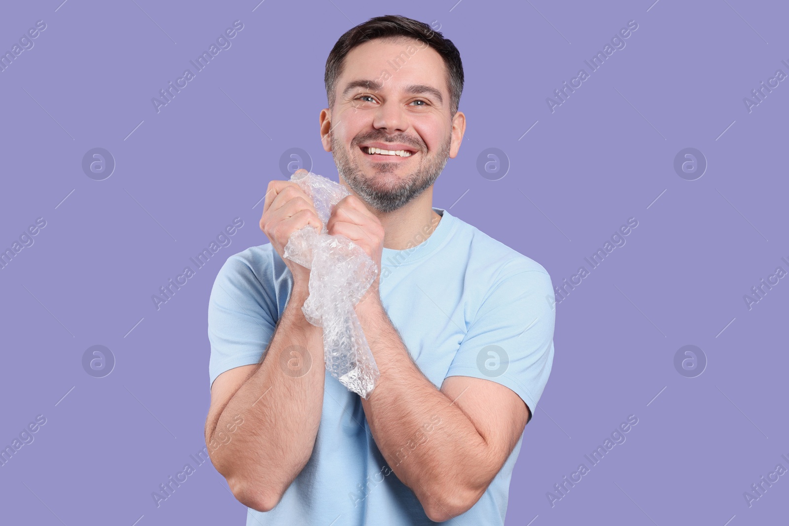 Photo of Happy man with bubble wrap on purple background
