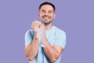 Happy man with bubble wrap on purple background