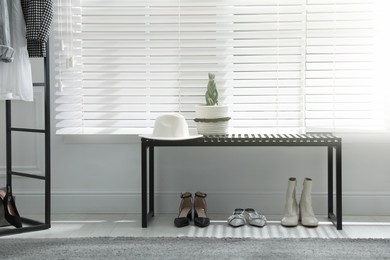 Photo of Bench with stylish women's shoes near window in dressing room. Interior design