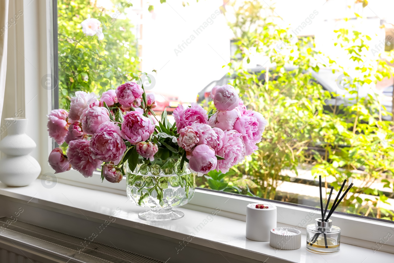 Photo of Beautiful pink peonies in vase on window sill. Interior design